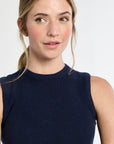 Woman wearing a navy sleeveless top against a white background