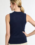 Woman wearing a navy blue sleeveless sweater against a white background