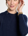 Woman wearing a navy blue sweater with a gold bracelet on a white background
