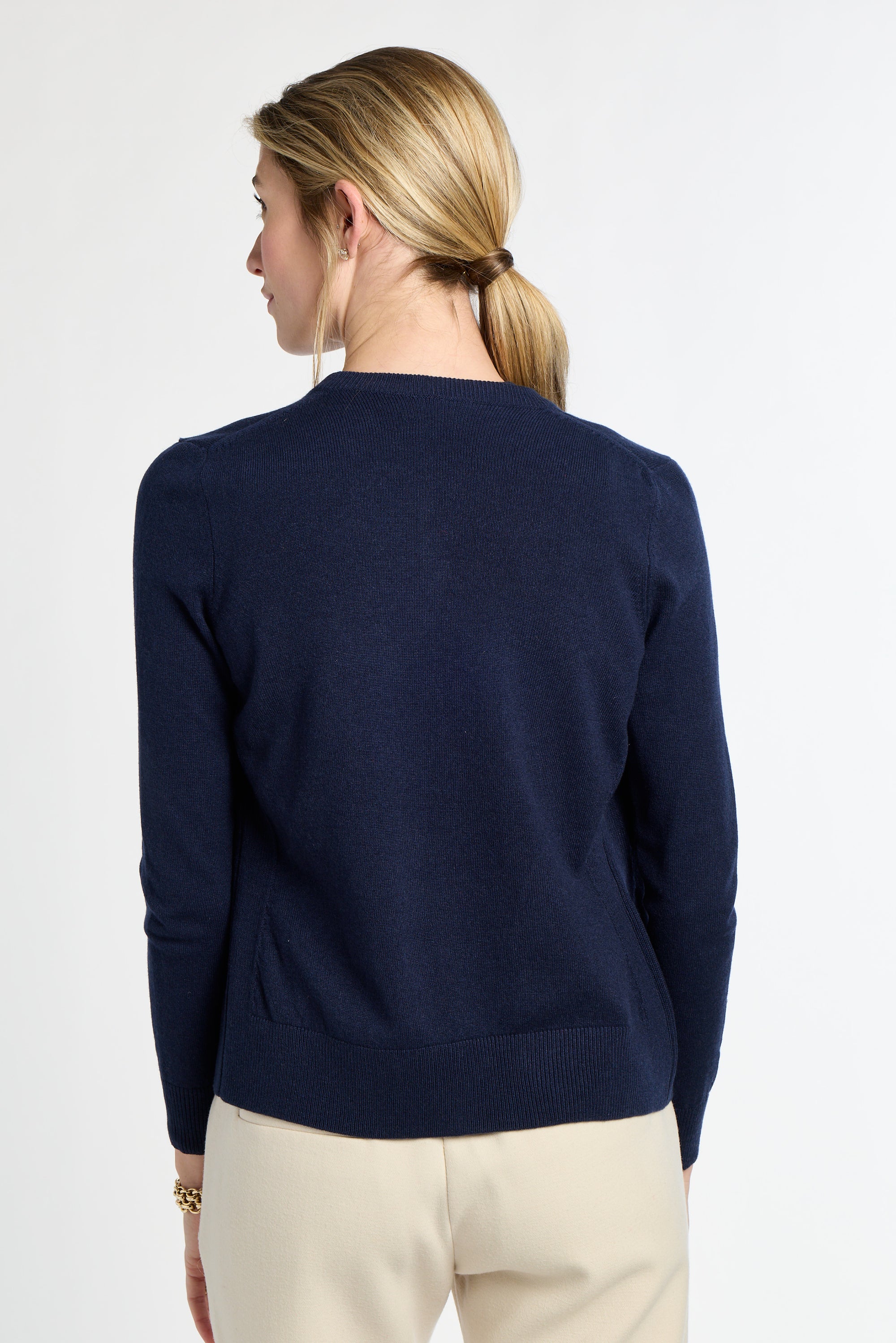 Woman wearing a navy sweater and beige pants on a white background