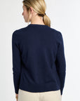 Woman wearing a navy sweater and beige pants on a white background