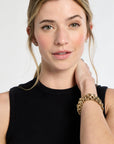 Woman wearing a black sleeveless top and gold bracelet on a white background