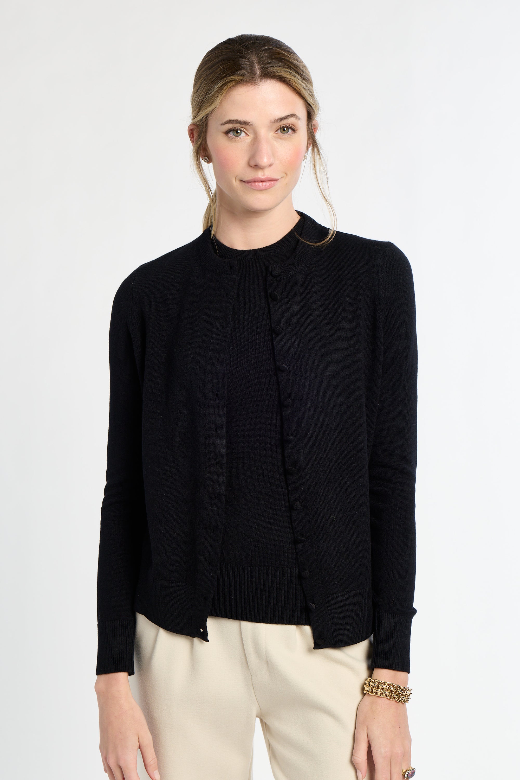 Woman wearing a black blouse and beige pants on a white background