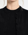 Close-up of a person wearing a black cardigan with buttons on a white background