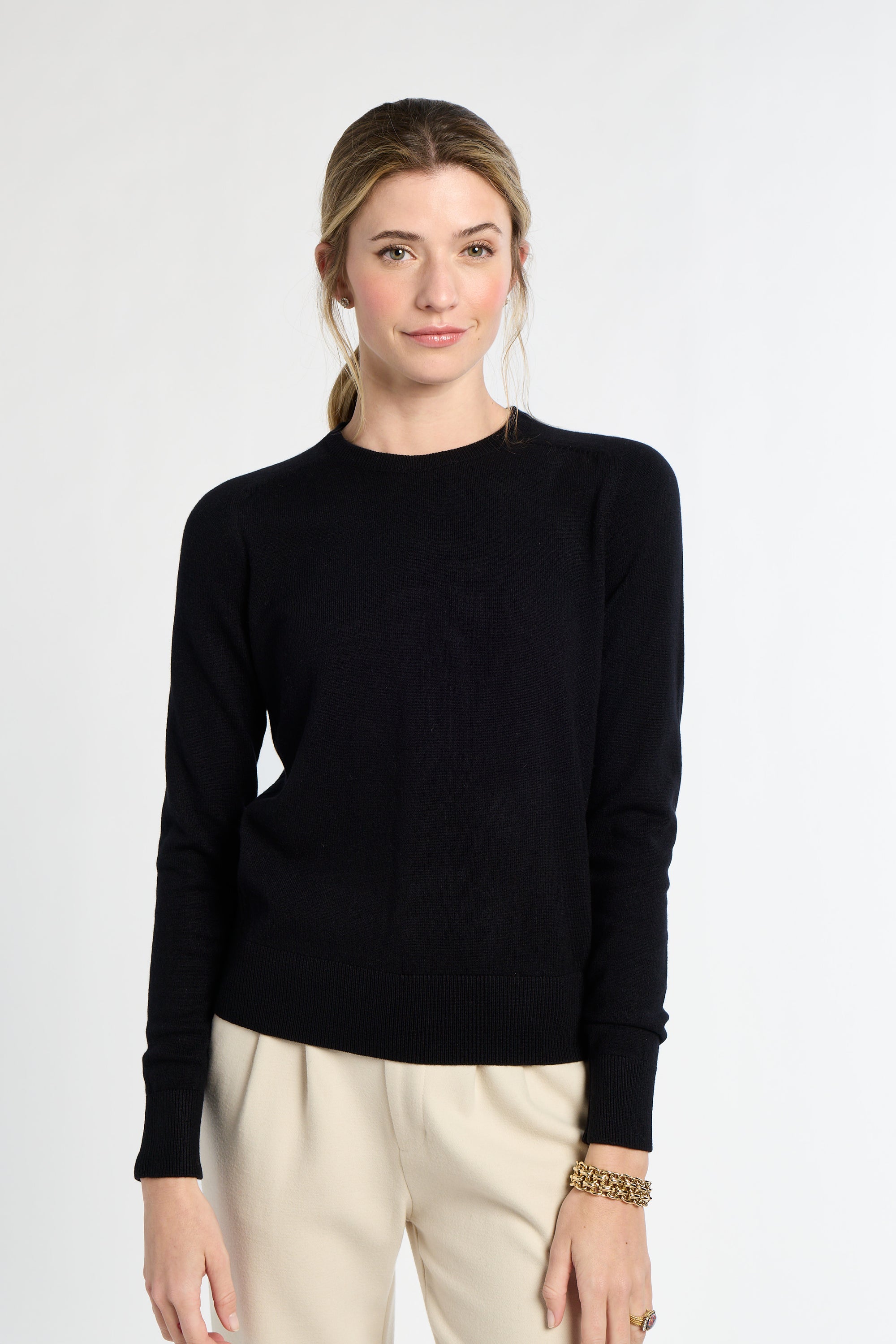Woman wearing a black sweater and beige pants on a white background