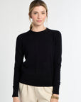 Woman wearing a black sweater and beige pants on a white background