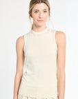 Woman wearing a sleeveless cream top on a white background