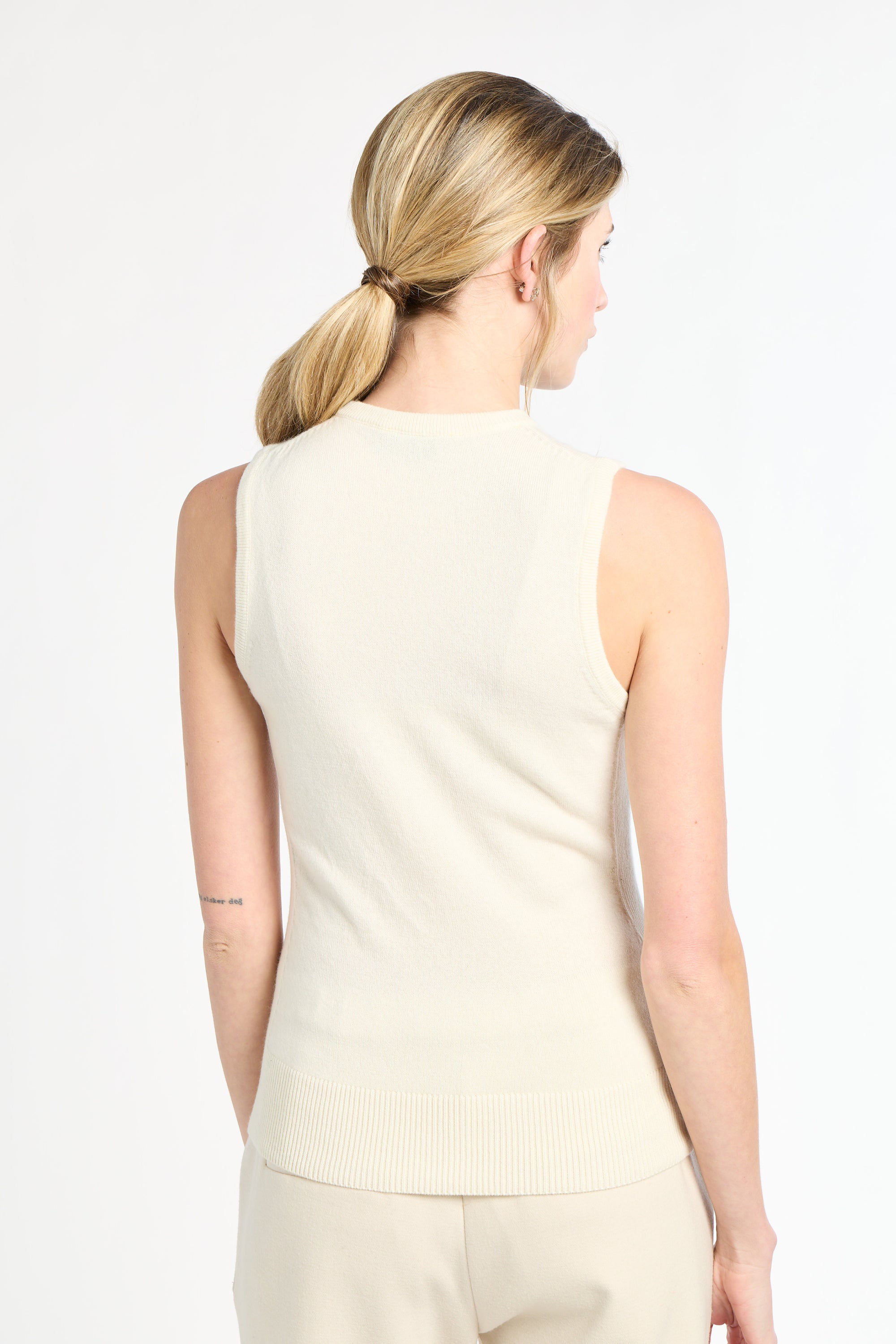 Woman wearing a beige sleeveless top and pants on a white background