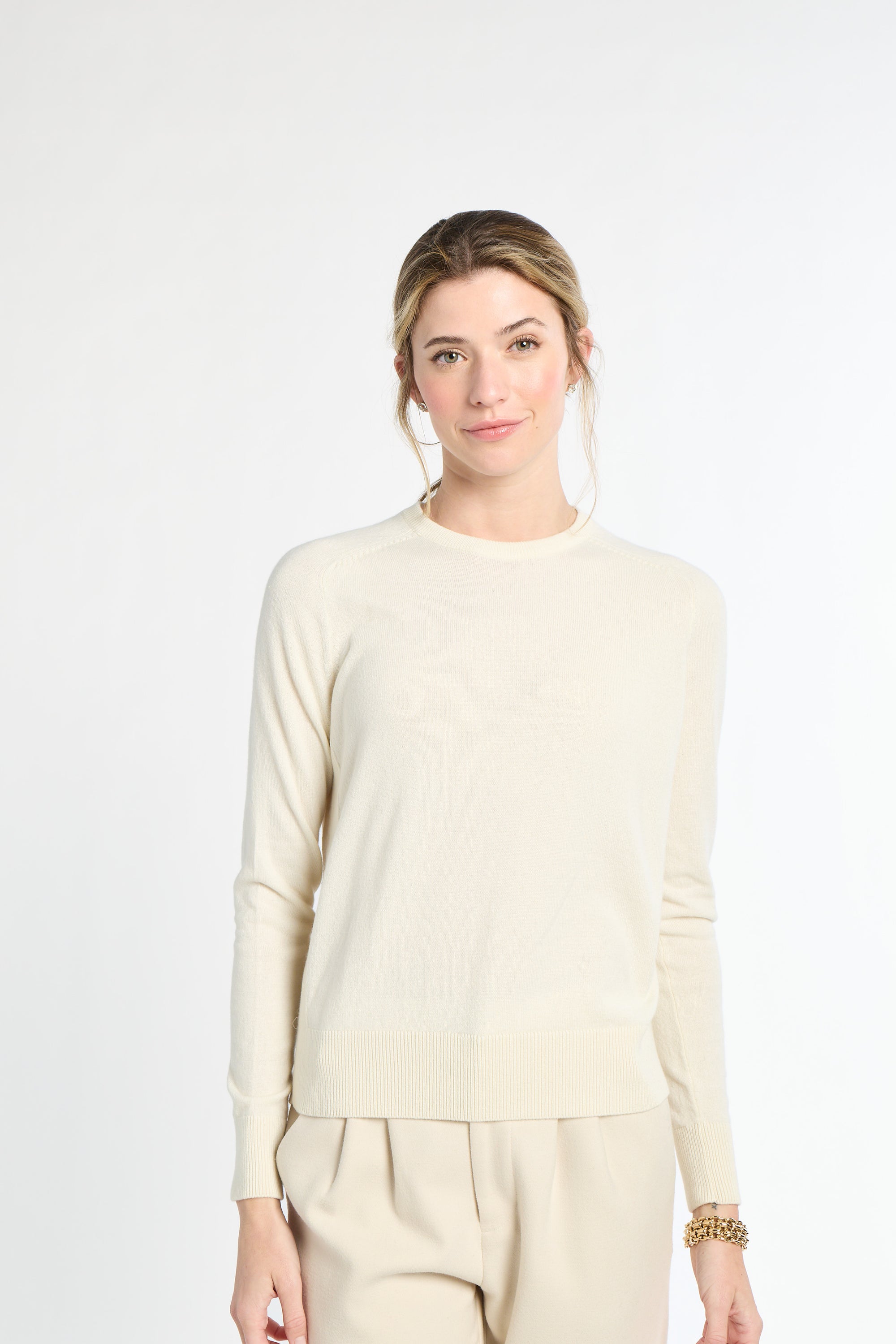 Woman wearing a beige sweater and pants on a white background