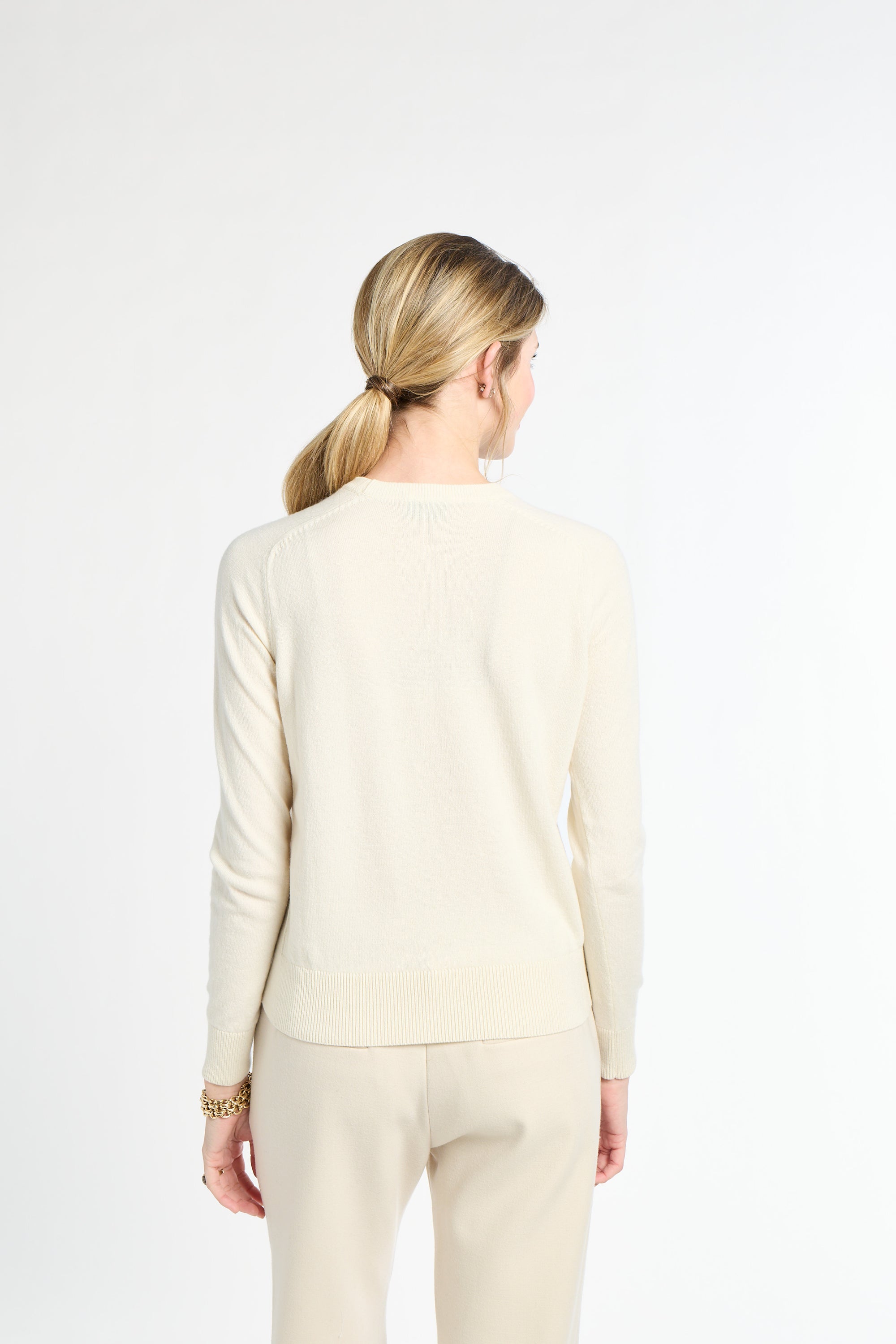 Woman wearing a beige long-sleeve top and pants on a white background