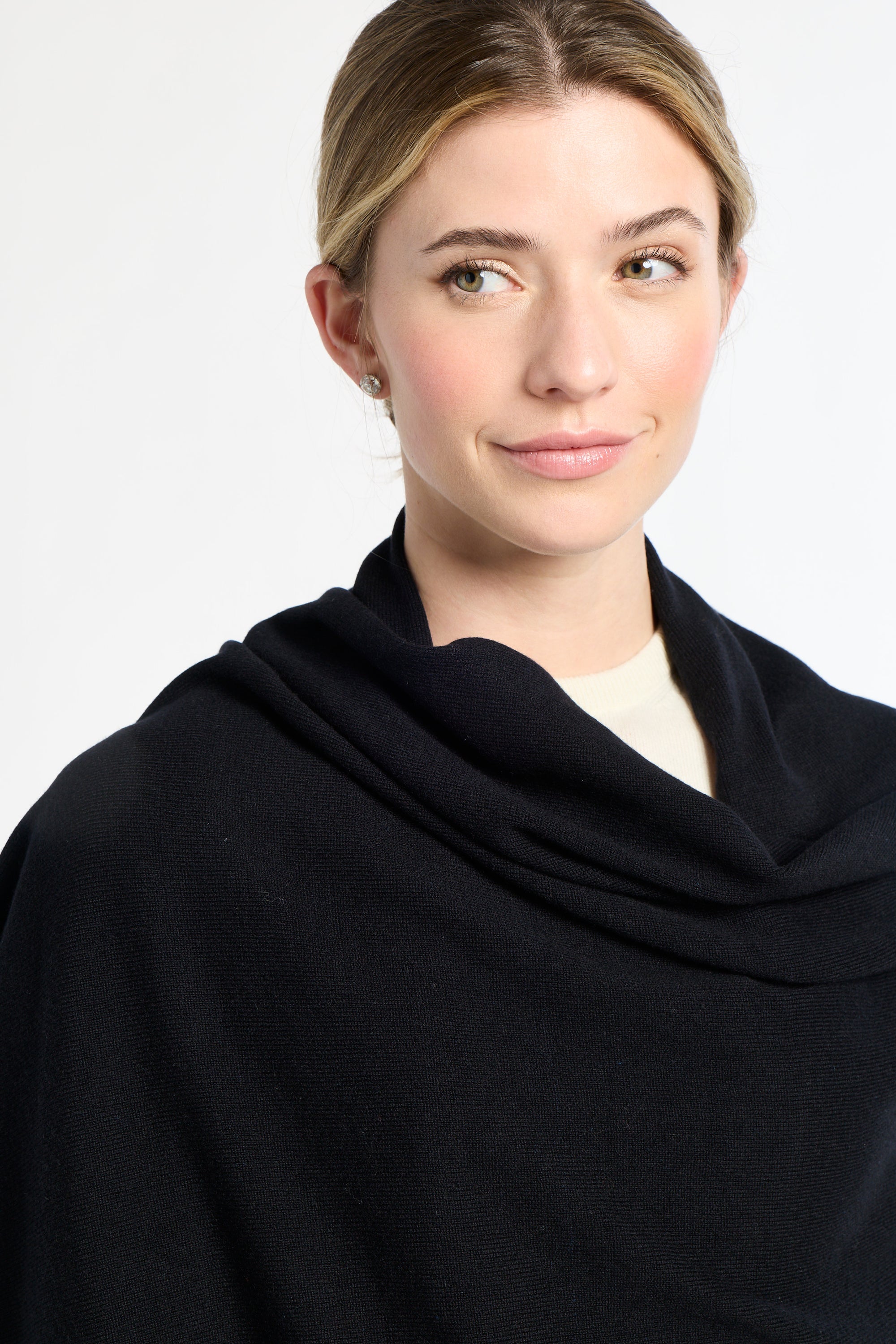 Woman wearing a black cowl-neck sweater against a white background