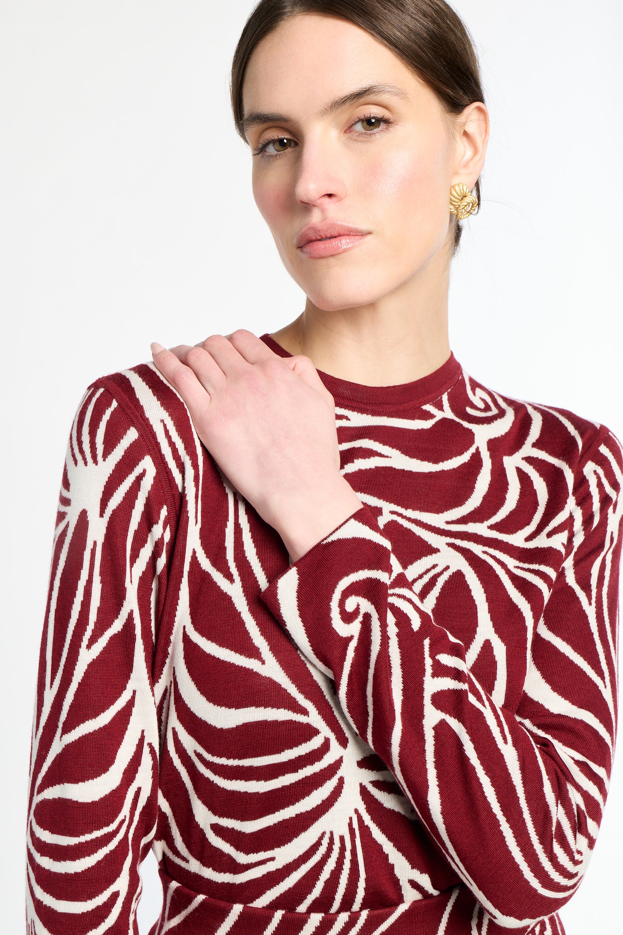 Woman wearing a red and white patterned sweater against a white background