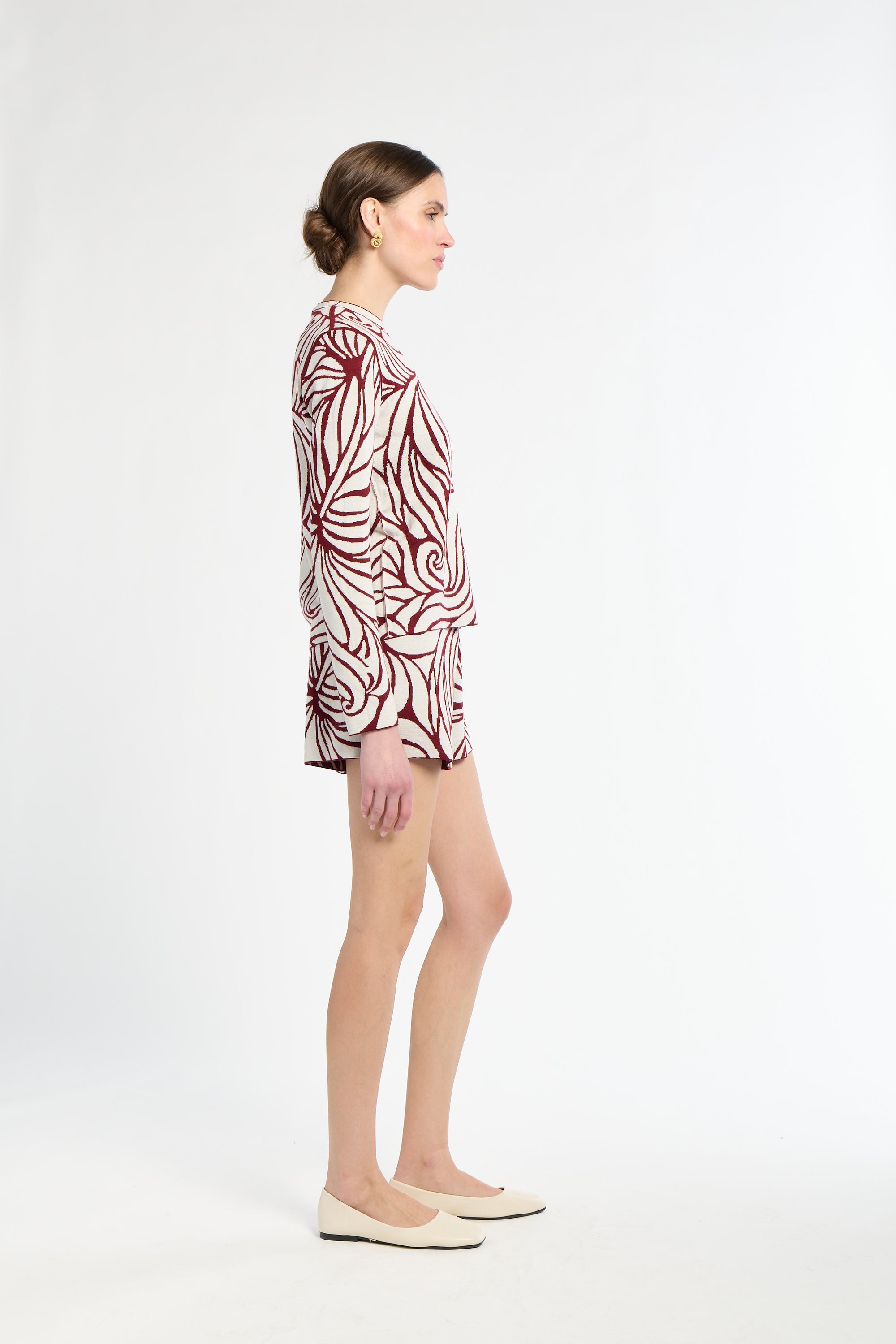 Woman wearing a patterned shirt and beige tights on a white background