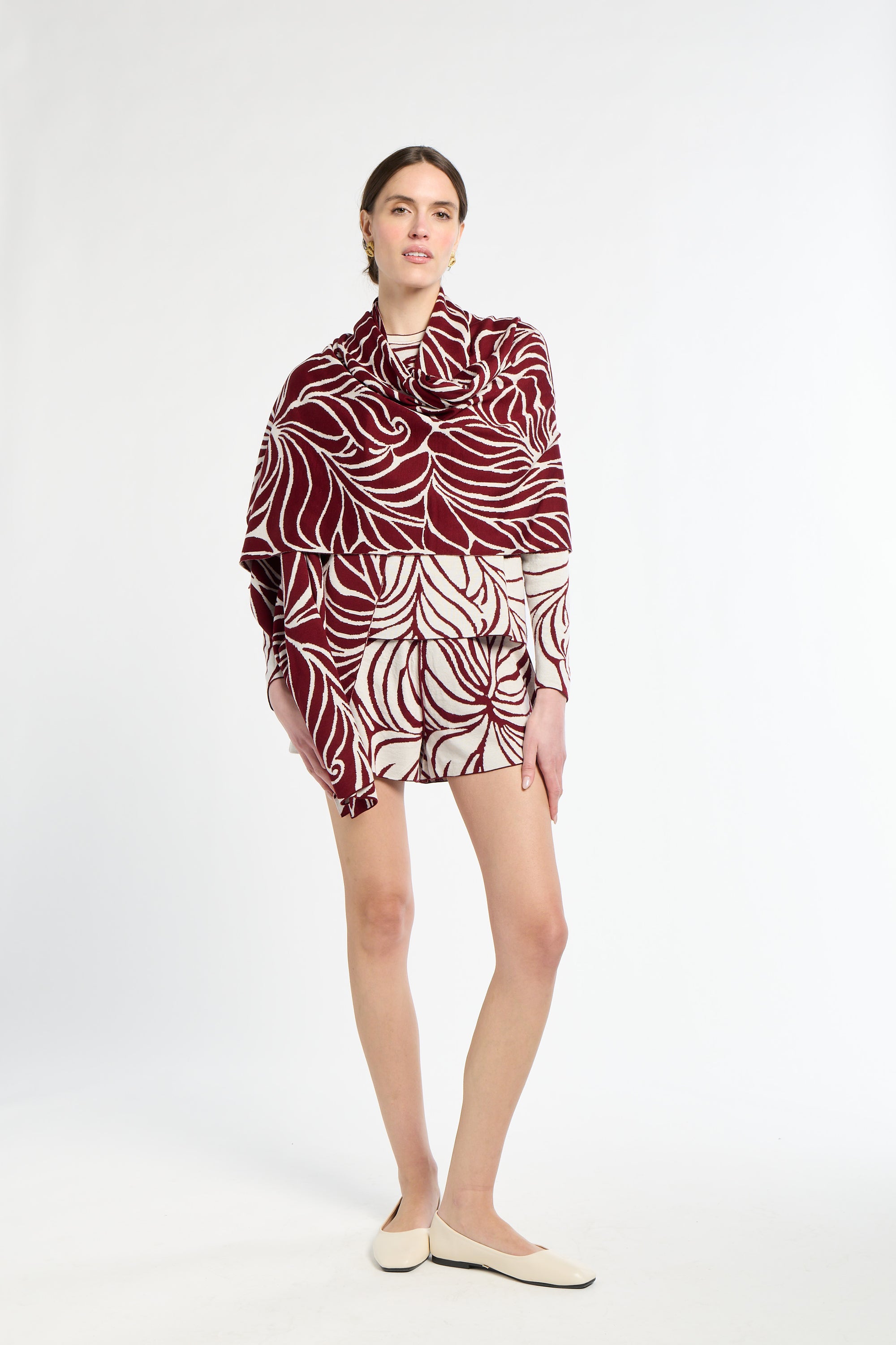 Woman wearing a patterned dress with a red and white design on a white background