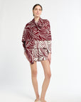 Woman wearing a patterned dress with a red and white design on a white background