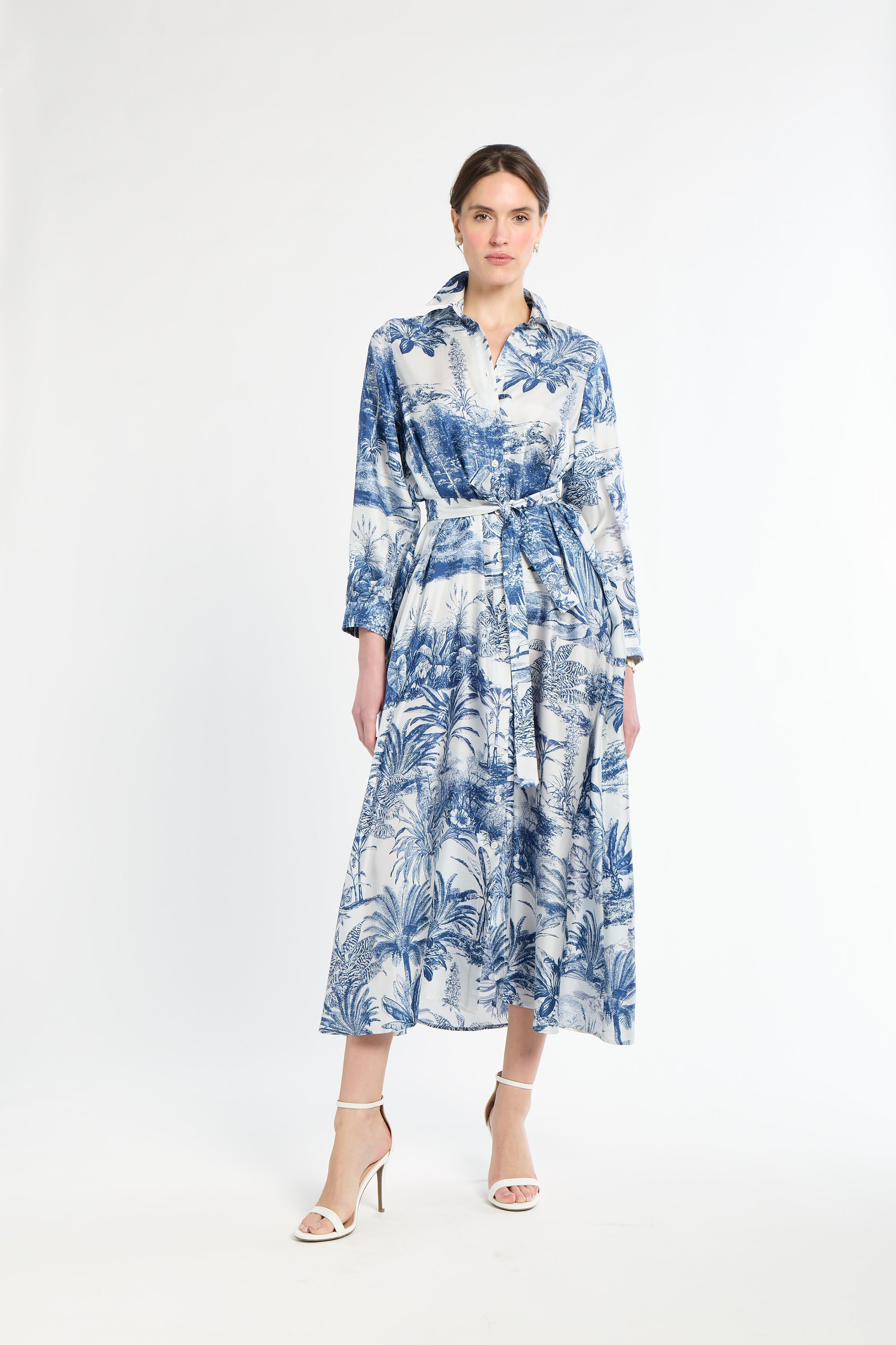 Woman wearing a long blue patterned dress on a white background