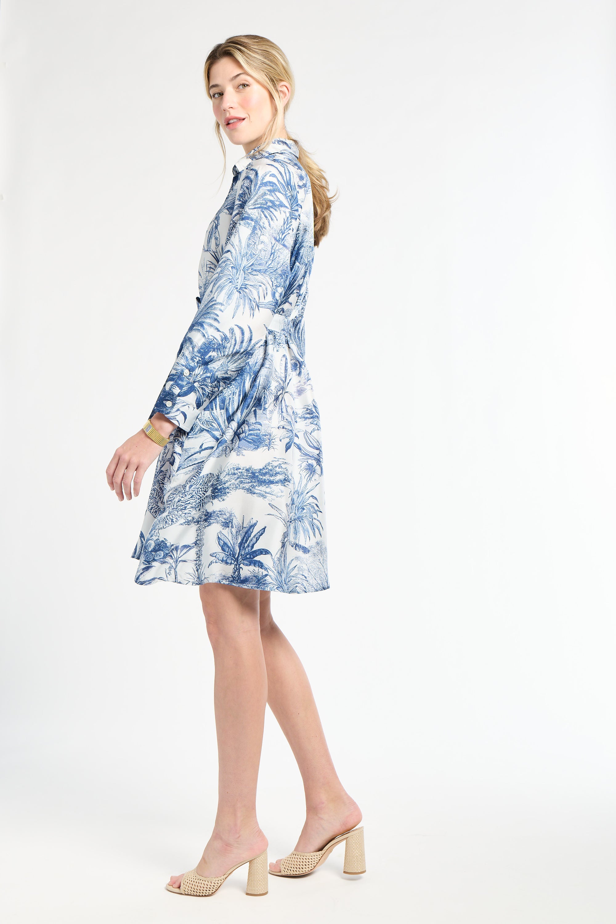 Woman modeling a blue floral dress in heels on a white background