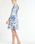 Woman modeling a blue floral dress in heels on a white background