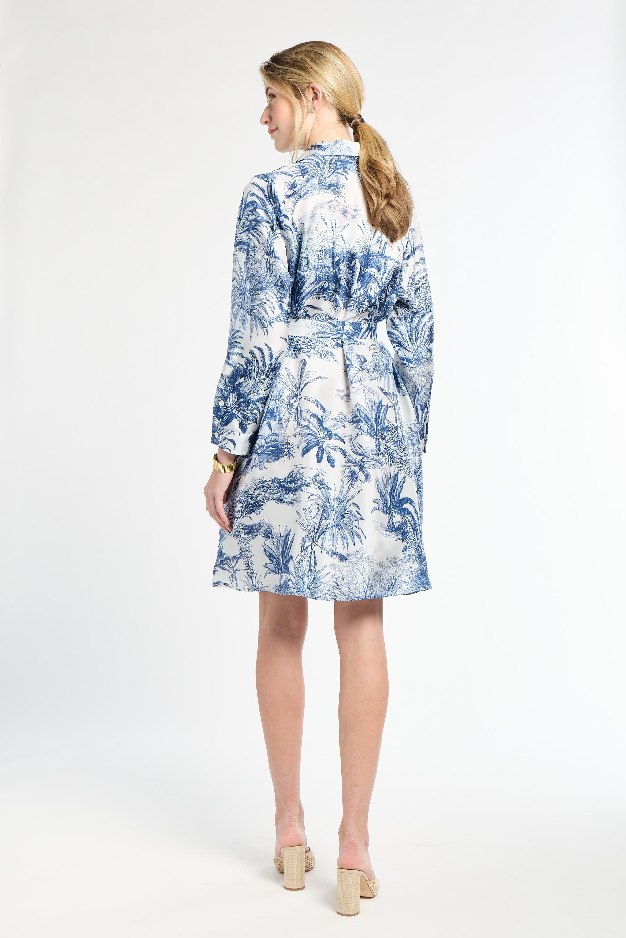 Woman modeling a blue and white mid-length dress on a white backdrop