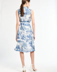 woman standing modeling a blue patterned dress with white heels on a white background