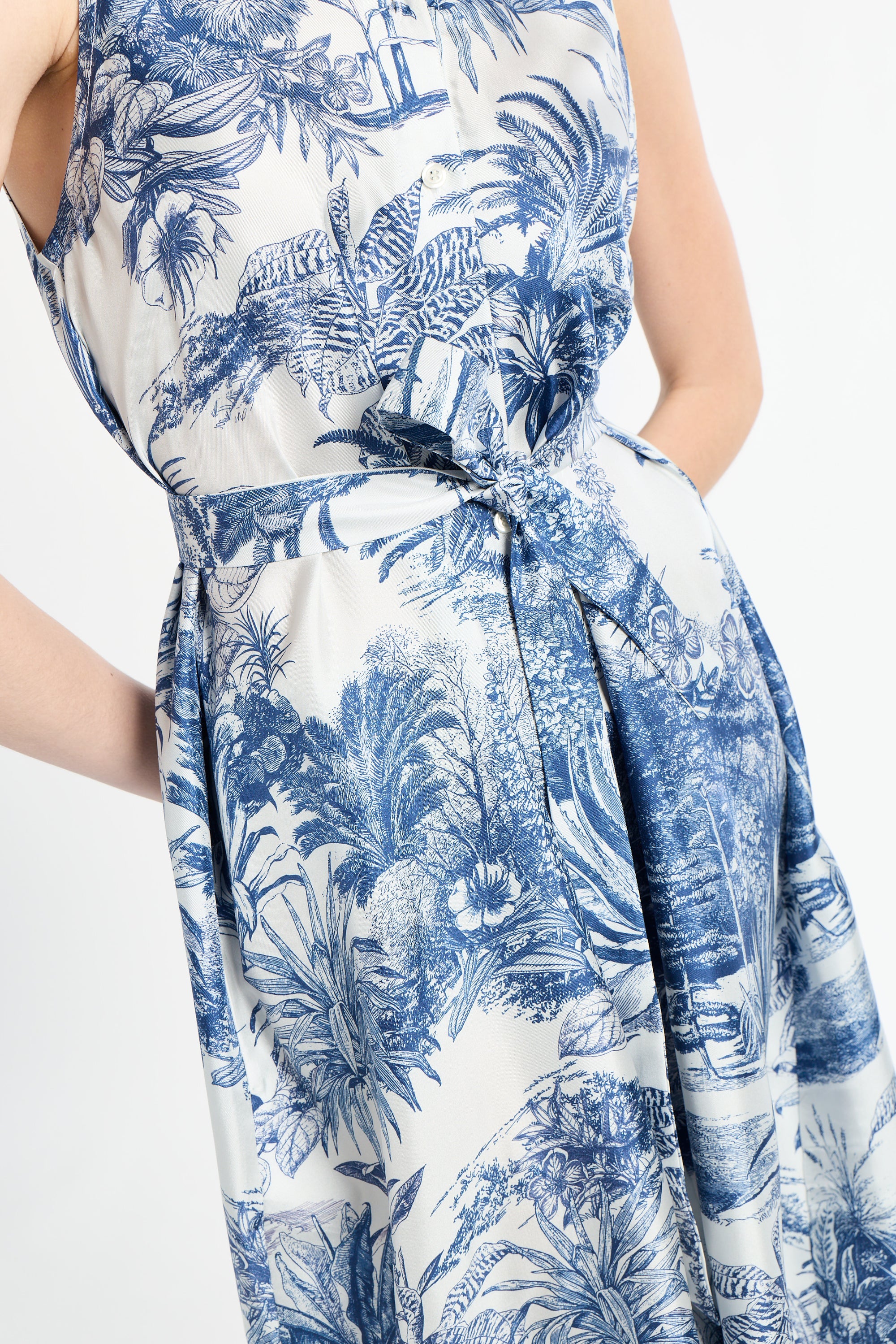 woman wearing sleeveless blue patterned dress with ribbon around waist