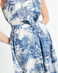 woman wearing sleeveless blue patterned dress with ribbon around waist