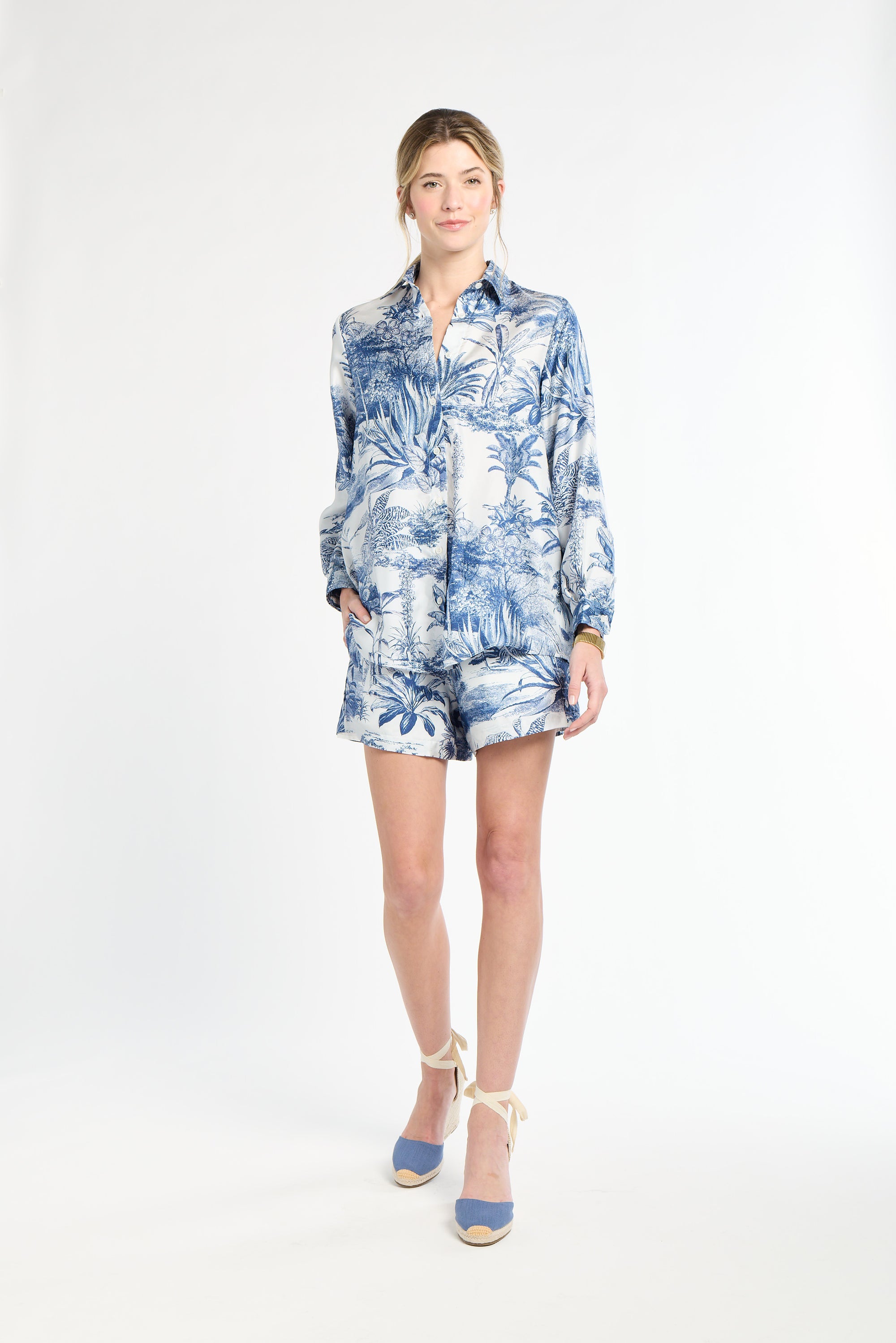 Woman wearing a blue and white blouse and shorts on a white background
