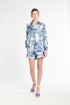 Woman wearing a blue and white blouse and shorts on a white background