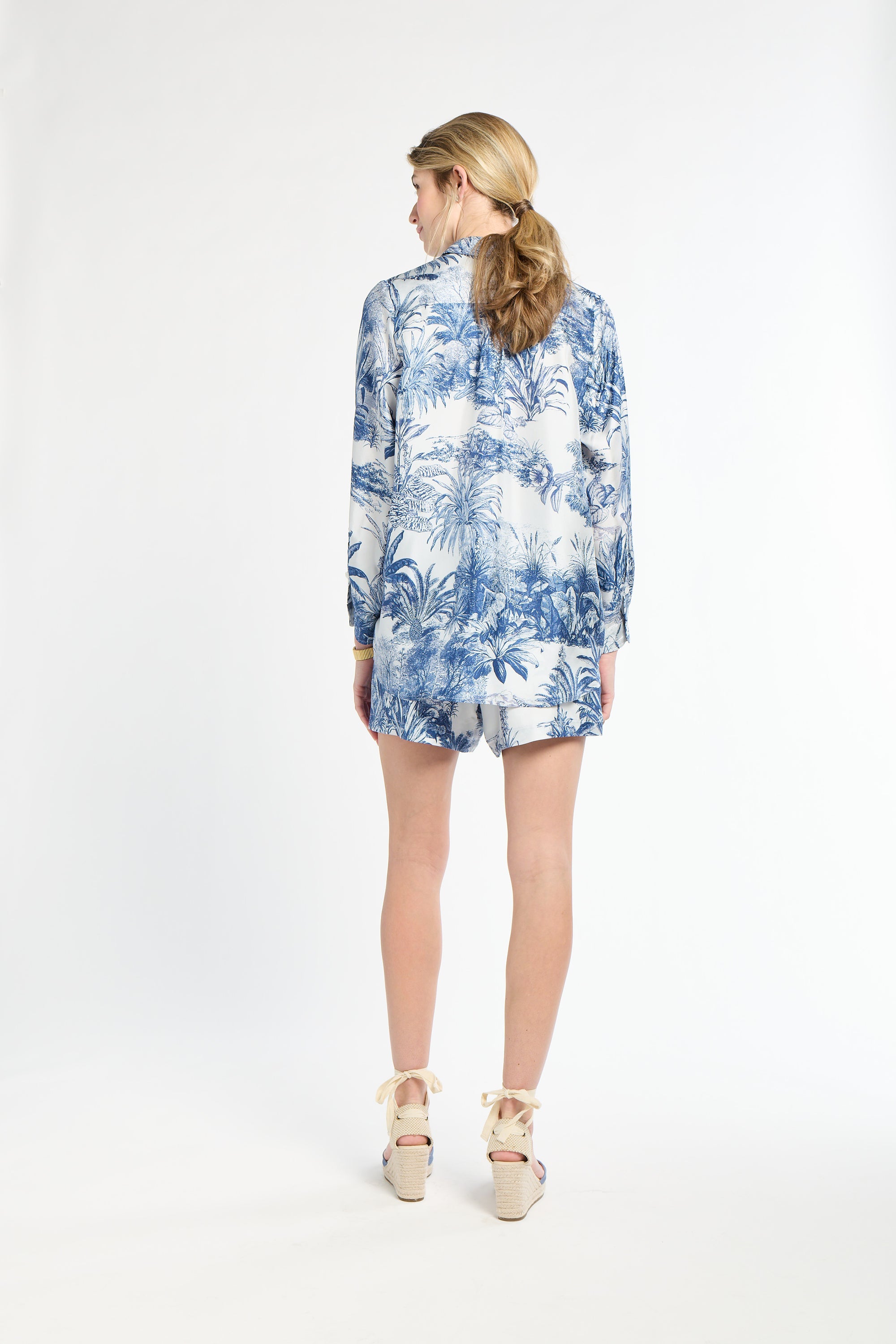 Woman wearing a long sleeve blue and white blouse on white background