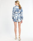 Woman wearing a blue and white floral blouse and shorts on a white background