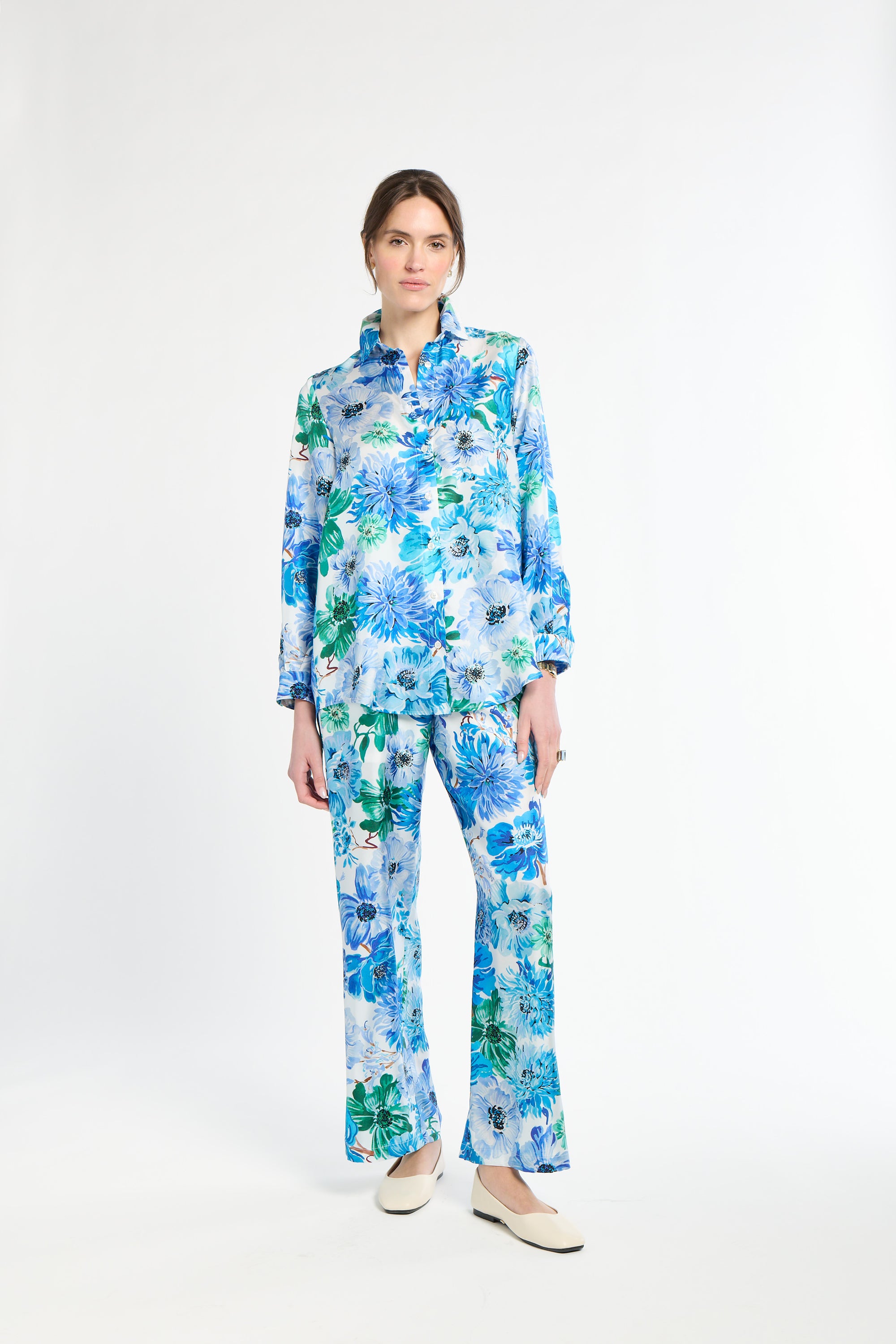 Woman wearing a blue and green floral shirt with matching pants on a white background