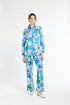 Woman wearing a blue and green floral shirt with matching pants on a white background