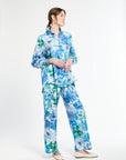 Side profile of woman wearing a blue and green floral shirt with matching pants on a white background