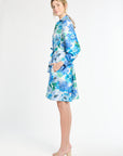 Woman wearing a belted silk blue floral dress on a white background