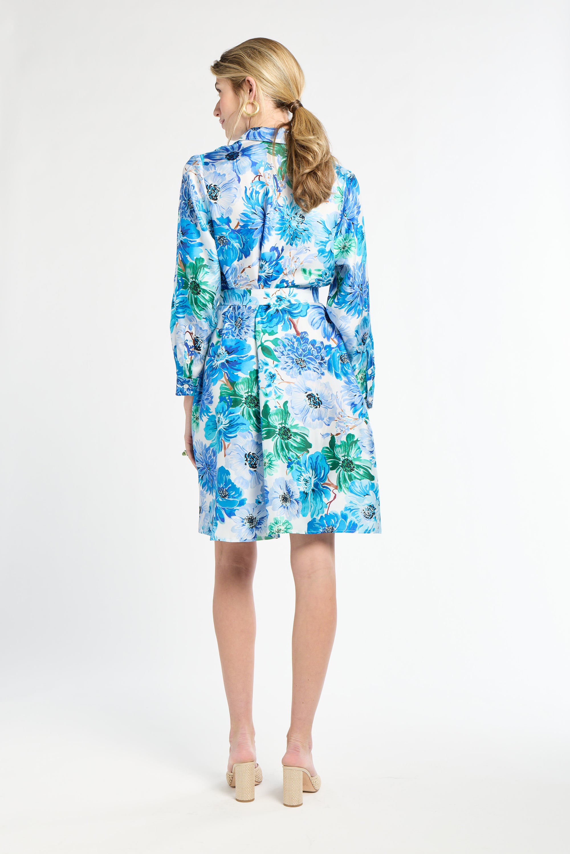 Back of woman wearing a blue and green floral dress on a white background