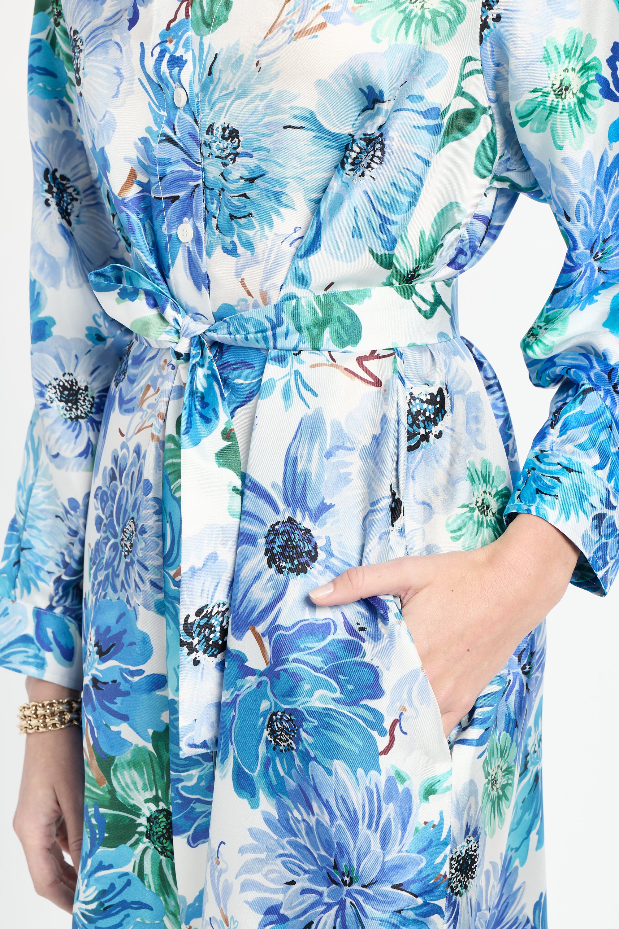 Close up of woman wearing silk shirt dress with blue and green floral pattern