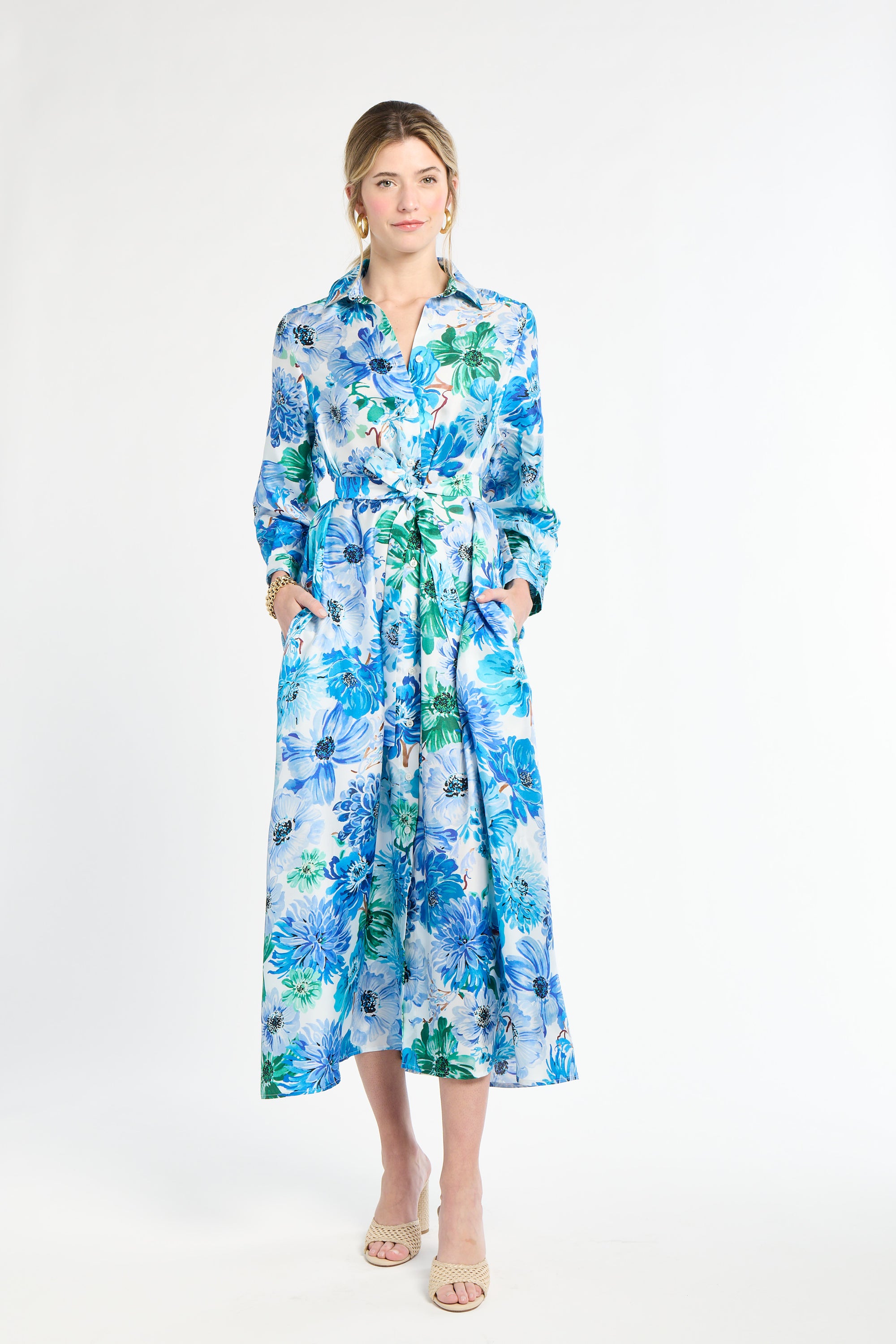 Woman wearing silk shirt dress with blue and green floral pattern on a white background