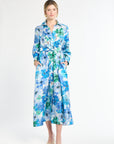 Woman wearing silk shirt dress with blue and green floral pattern on a white background