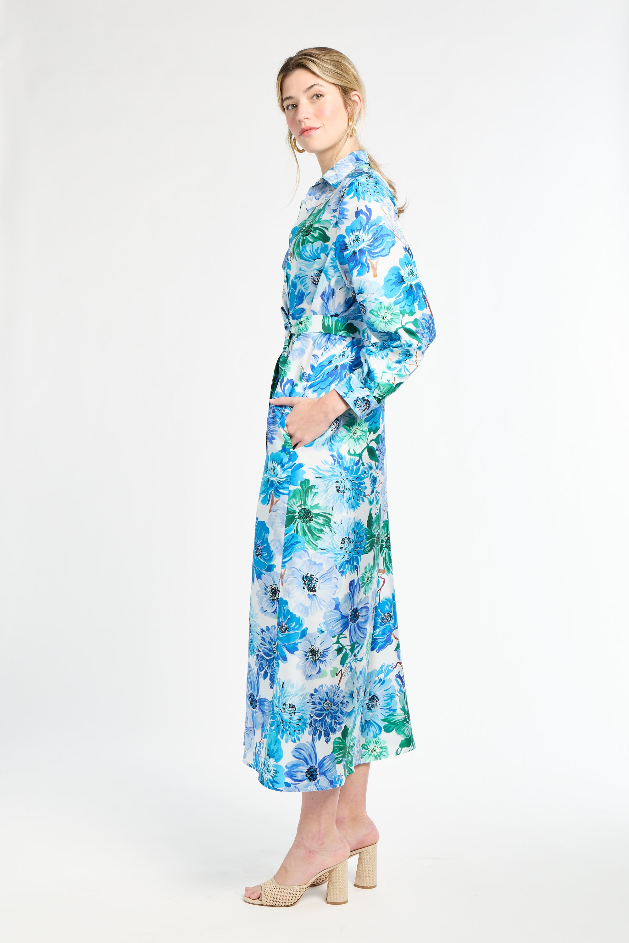 Side profile of woman wearing silk shirt dress with blue and green floral pattern on a white background