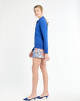 Woman wearing a blue outfit with floral shorts on a white background