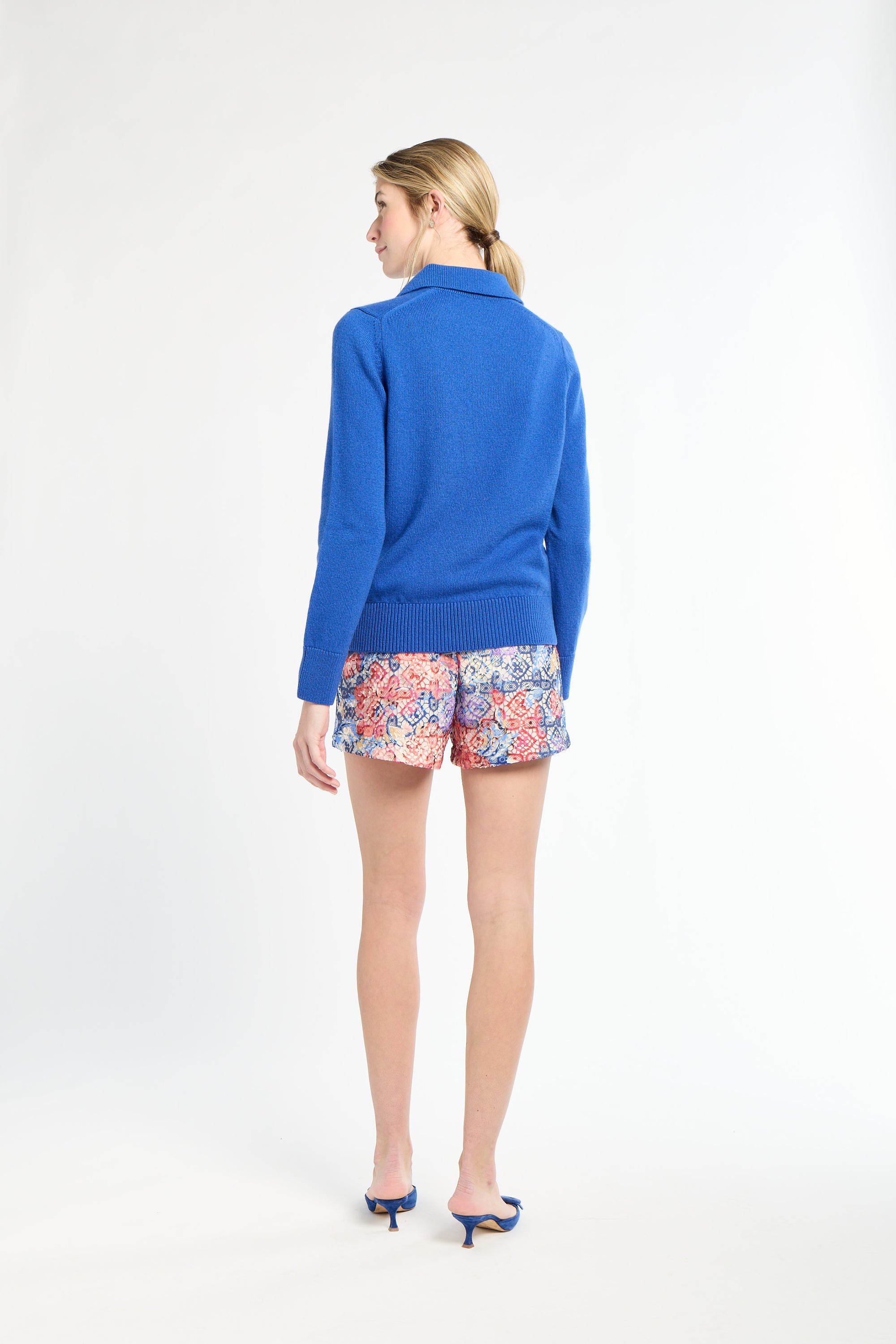 Woman wearing a blue sweater and colorful shorts on a white background