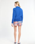 Woman wearing a blue sweater and colorful shorts on a white background