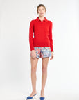 Woman wearing a red sweater and patterned shorts on a white background