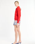 Woman wearing a red sweater and patterned shorts on a white background