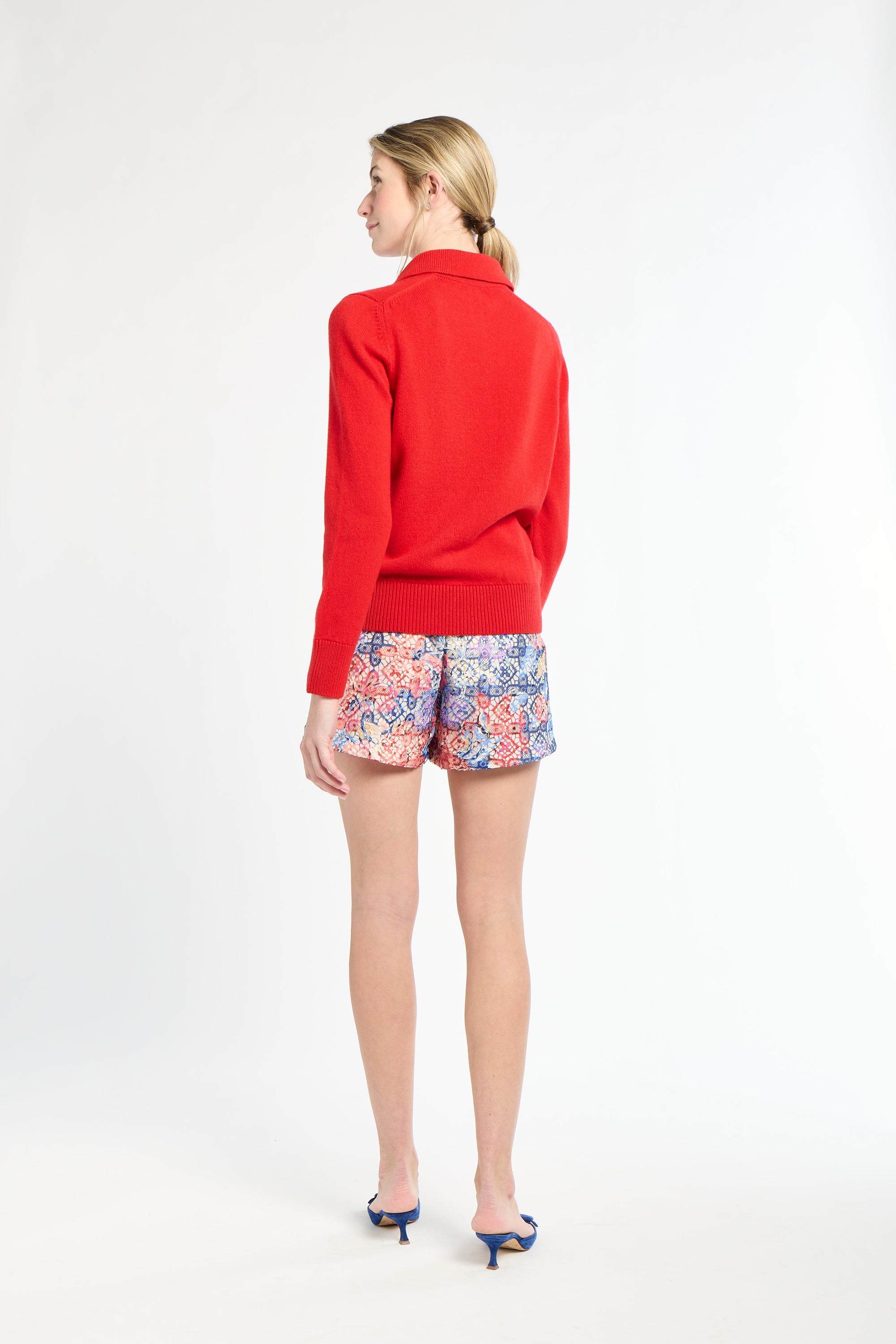Woman wearing a red sweater and colorful shorts on a white background