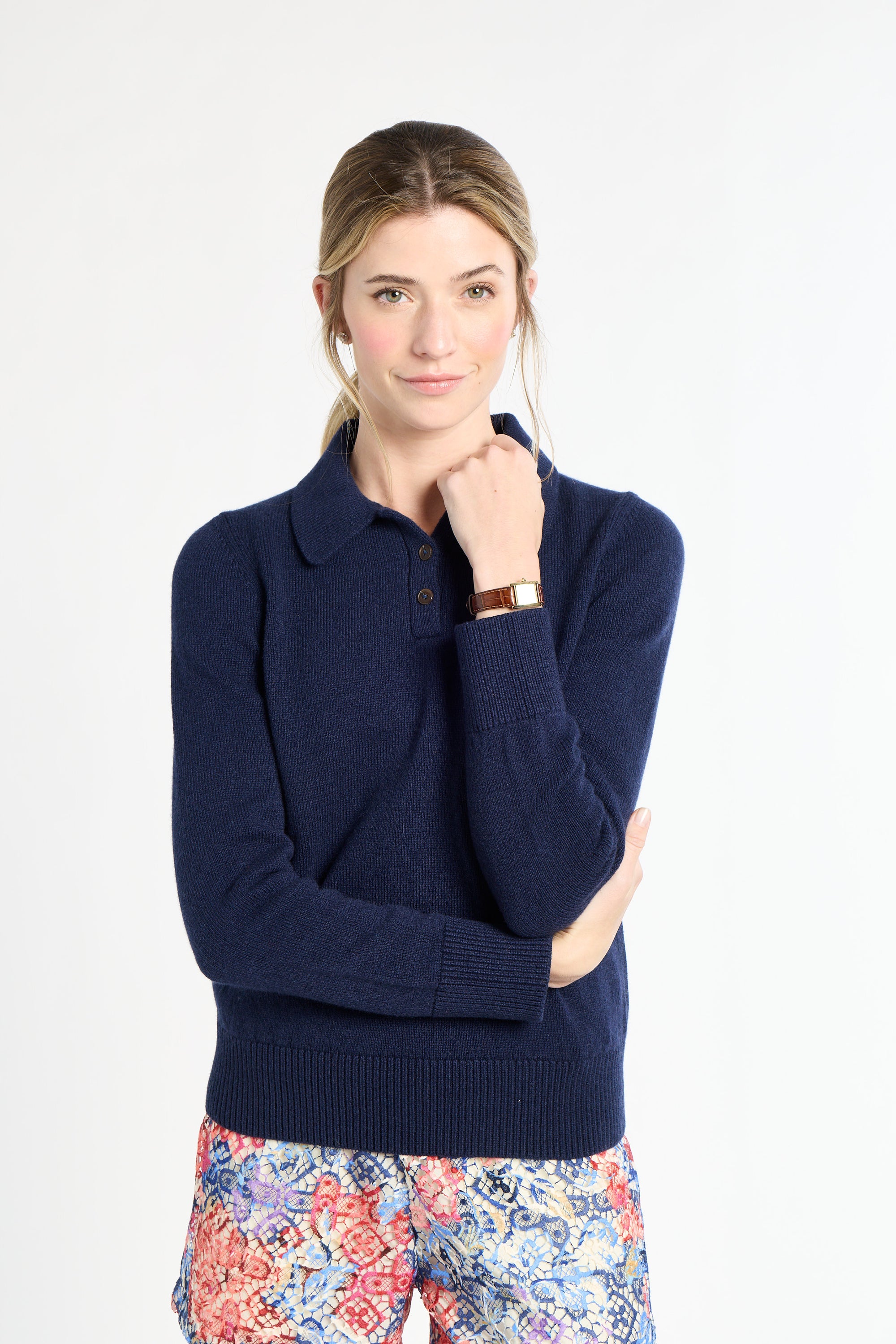 Woman wearing a navy sweater with floral pants on a white background