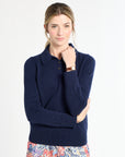 Woman wearing a navy sweater with floral pants on a white background