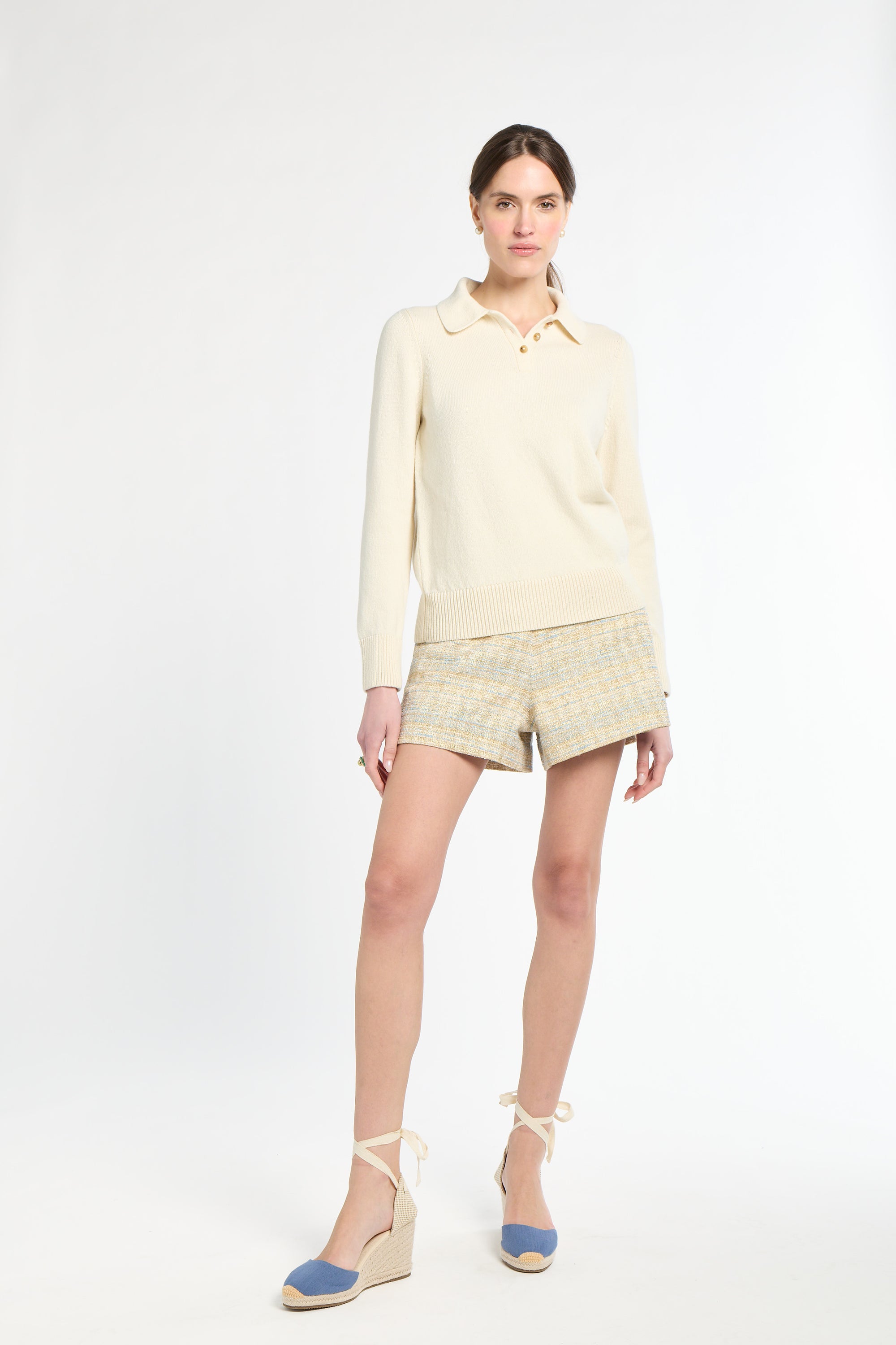 Woman wearing a light yellow outfit with shorts on a white background