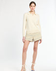 Woman wearing a light yellow outfit with shorts on a white background