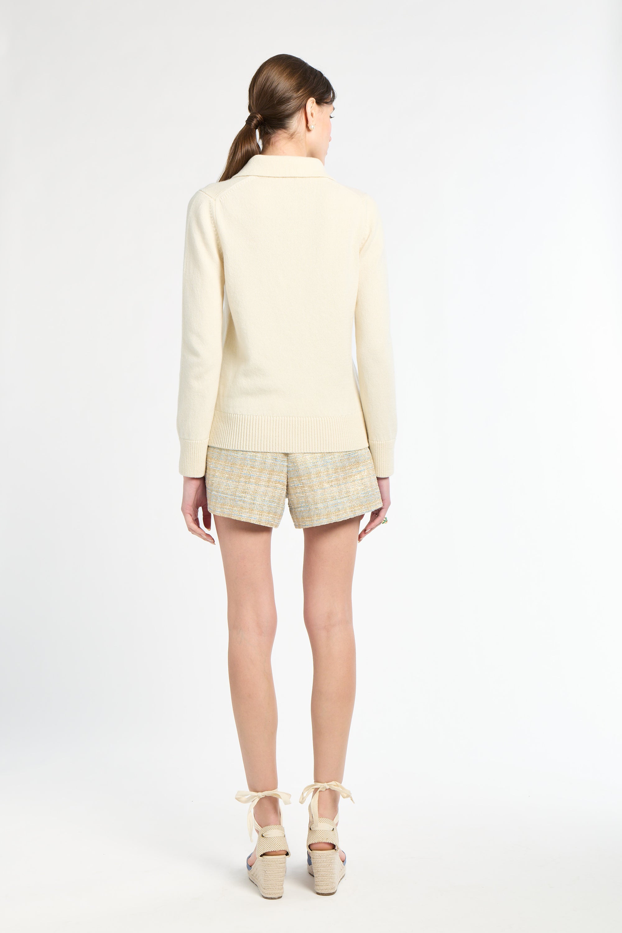 Woman wearing a light yellow outfit with plaid shorts on a white background